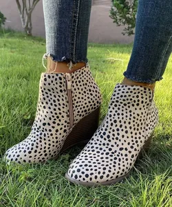 Primer plano de botines de cuña retro con estampado de leopardo en césped