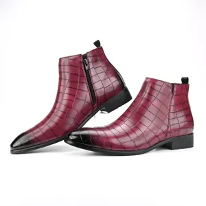Dettaglio della texture a coccodrillo bordeaux sugli eleganti stivaletti Chelsea da uomo