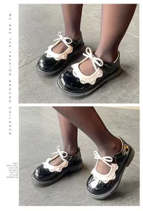 Detalle de zapatos Mary Jane de charol negro para niña con encaje blanco y lazos.