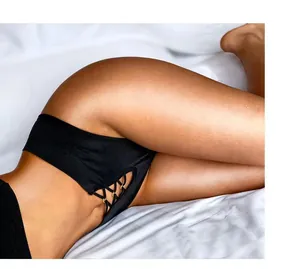 Détail d'un string noir sexy sans couture avec laçage latéral et petits anneaux dorés.