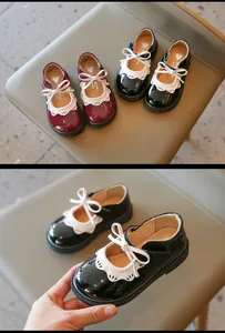 Primer plano de zapatos de charol negro para niña con borde de encaje blanco y lazo