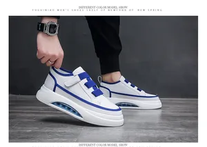 Side view of a white and blue men's sneaker being held, showing the air cushion sole detail