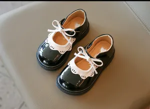 Primer plano de zapatos de charol para niñas con encaje blanco y lazo decorativo