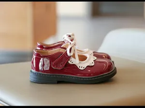 Vista lateral de zapatos de charol granate para niña con borde festoneado blanco