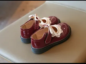 Vista trasera de zapatos burdeos de charol para niña con ribete festoneado y lazo