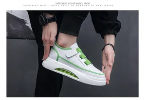 Close-up of stylish white sneakers for men featuring green accents and visible air cushion