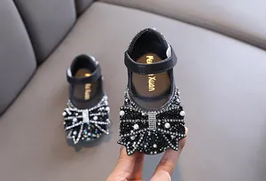 Detailopname van zwarte prinsessenschoenen voor meisjes met strass-strik en parels.