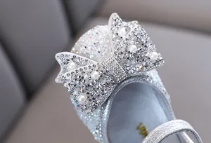 Detailopname van de fonkelende strik met strass en parels op zilveren meisjesschoen