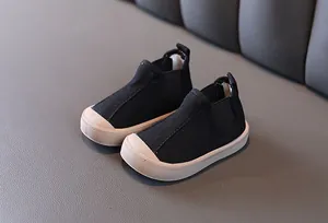 Close-up of black toddler canvas shoes with a slip-on design and durable rubber toe cap.