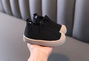 Close-up of warm black high-top canvas baby shoes with beige anti-slip rubber soles.