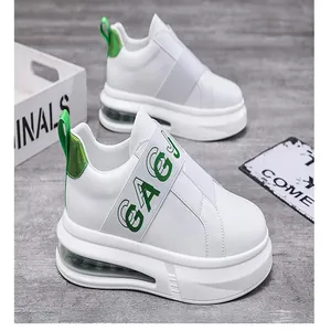 Close-up of white chunky slip-on sneakers with green elastic strap and air sole