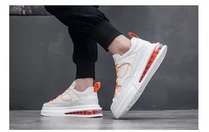 Vista lateral de zapatillas blancas para hombre con suela de aire naranja visible.