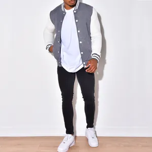 Vollansicht eines Mannes in grau-weißer College-Jacke und schwarzer Skinny-Jeans