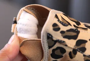 Macro detail view of warm white plush lining in kids leopard print canvas winter shoe
