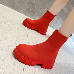 Detailed view of vibrant red knit sock boots with thick chunky lug soles for women.
