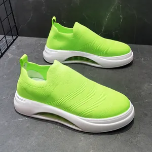 Vista dettagliata di eleganti sneakers fly-knit verde neon traspiranti con suole bianche.