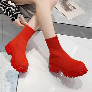 Vibrant red knitted high-top sock boots with a chunky platform sole worn by a model