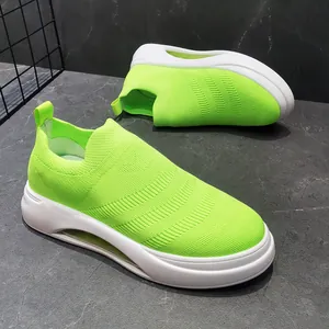 Vista dettagliata di sneaker da uomo in maglia traspirante verde neon con suole bianche.
