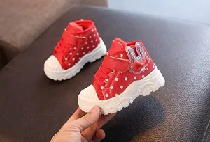 Close-up of red polka dot girls' winter boots with sequined bunny ears and fleece lining