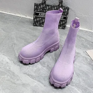 Detailed macro shot of stylish purple knitted thick-soled sock boots on marble surface.