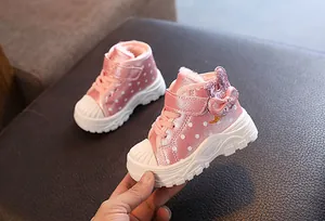 Close-up of pink fleece-lined toddler winter boots with sparkly bow and polka dots