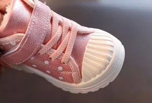 Close-up of pink polka dot kids' winter boots with plush lining and rubber toe cap