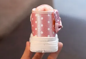 Detail view of the back of a pink polka dot girl's snow boot featuring a shiny bow.