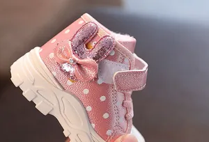Detail of cute sequined bunny and bow on pink polka dot winter baby boots