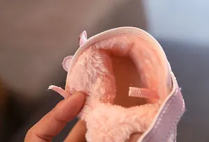 Macro shot showcasing the thick and warm pink plush lining inside winter snow boots for kids.