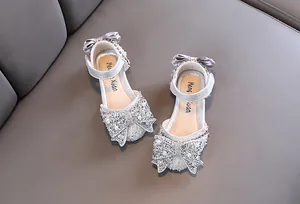 Detail of sparkling silver girls' princess shoes with elegant bow and pearl accents.
