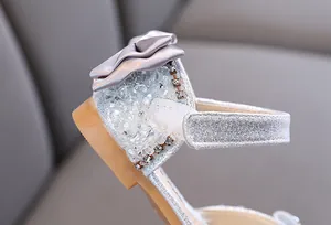 Close-up of silver glitter girls princess shoe with satin bow and rhinestone details.