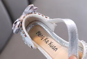 Close-up of silver girls princess shoe featuring a satin bow and delicate pearl accents
