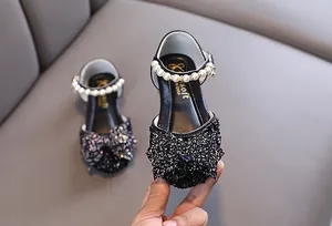 Détail en gros plan de chaussures de princesse à paillettes noires avec bride en perles