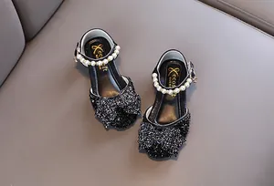 Vue détaillée des chaussures de princesse à paillettes noires pour filles avec perles et nœud.