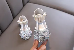 Gros plan de chaussures de princesse argentées pailletées avec perles et nœud