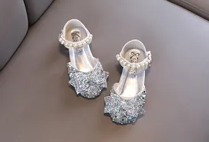 Gros plan de chaussures de princesse argentées pailletées pour filles avec nœud et perle