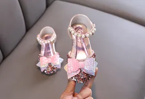 Détail du nœud pailleté rose et de la bride de cheville en perles pour chaussures fille