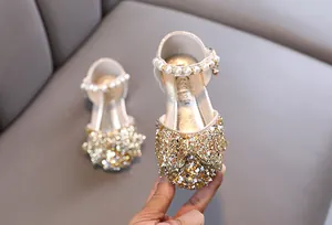 Gros plan de chaussures de princesse dorées pour filles avec un nœud pailleté
