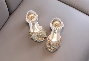 Vue détaillée de chaussures de princesse à paillettes dorées pour filles avec nœud et perle