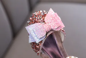 Gros plan sur le nœud rose pailleté et les strass des chaussures de danse princesse