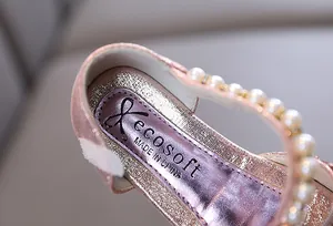 Gros plan de chaussure de princesse rose pailletée avec bride en perles élégantes.