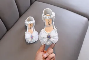 Close-up view of silver glitter girl's princess shoes with mesh bow and pearl details