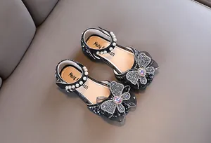 Close-up of black sparkly girls princess shoes with pearl straps and sequined bow