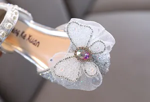 Detail showing the intricate mesh bow and sparkling rhinestones on silver girls' shoes