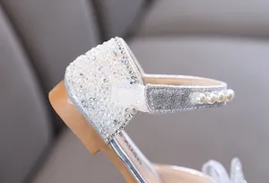 Close-up detail of silver girl's princess shoe featuring rhinestones and pearl strap
