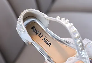Close-up detail of girls silver princess shoe featuring elegant pearls and rhinestone accents