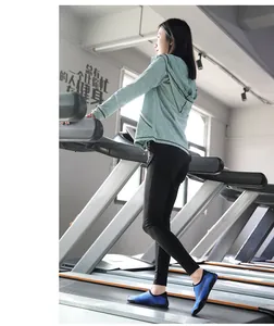 Woman wearing blue breathable and non-slip yoga water shoes on a treadmill in a gym setting