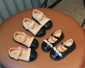 Vintage-Mädchen-Mary-Jane-Schuhe mit Perlenriemen und glänzender schwarzer Lackspitze.