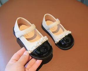 Nahaufnahme der zweifarbigen Mädchen-Lederschuhe mit Perlen-Dekor und Klettverschluss.