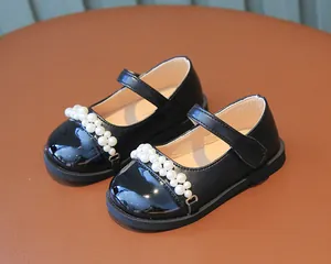 Detailansicht von schwarzen Mädchenschuhen mit eleganten Perlenriemen-Akzenten.
